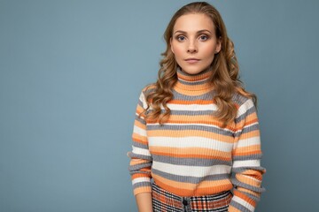 Wall Mural - Young charming fascinating self-confident serious blond woman wearing casual striped pullover isolated over blue background with free space