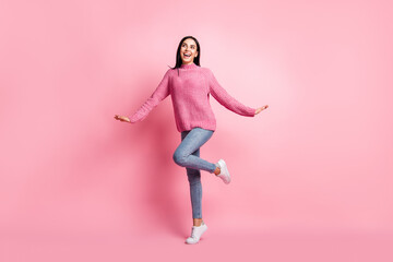 Wall Mural - Full length photo portrait of cute dreamy girl standing on one leg isolated on pastel pink colored background