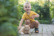 Little boy playing with a cat outdoors.