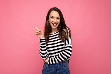 Wall Mural - Portrait of beautiful fascinating emotional positive joyful happpy female promoter pointing to the side at copy space for advertising wearing hipster outfit isolated over background wall with empty