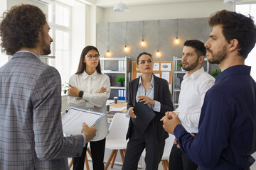 Young serious and smart people colleagues in the office discuss and plan a business plan for a new future project. Each member of the team makes their proposals for the project. Concept of teamwork.