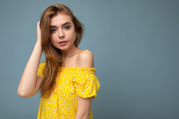 Wall Mural - Young beautiful dark blonde woman with sincere emotions isolated on background wall with copy space wearing stylish summer yellow dress. Positive concept