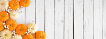 Autumn Corner Border Of Orange And White Pumpkins And Berries On A White Wood Background. Top Down View With Copy Space.