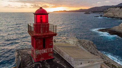 Wall Mural - Aerial view of the red lighthouse of La Madonetta in Bonifacio, at the southern tip of the island of Corsica in France - Sunset over the limestone cliffs of Bonifacio in the Mediterranean Sea