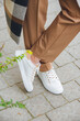 © Mykola - Closeup photo of beautiful fashionable woman wearing checkered long coat, beige pants, white blouse and sneakers.