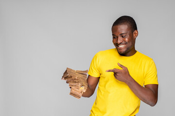 Wall Mural - young african man holding a lot of cash pointing to it excitedly