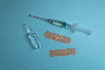 ampoule, syringe and patches lying on blue background