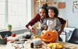 © JenkoAtaman - Ethnic father removing pulp from ripe pumpkin while carving jack o lantern with little son for Halloween