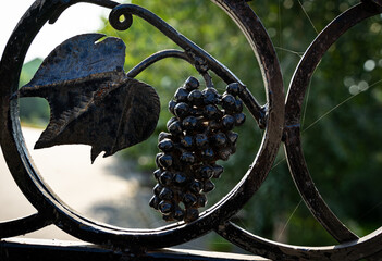 Wall Mural - Decorative wrought iron elements on a metal gate in the shape of a bunch of grapes and leaves