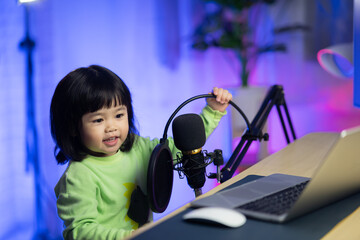 cute baby girl singing with headphone recording new song with microphone in the home recording studio