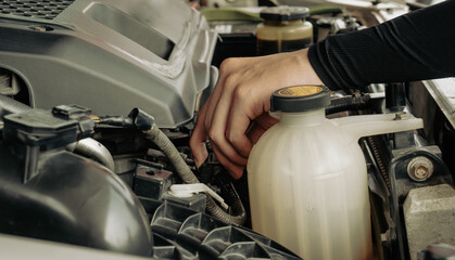 Maintenance technician is checking and diagnose car engines regularly before breakdown in order to minimize upkeep. Mechanic opens vehicle hood and inspecting engine condition in auto repair garage. 