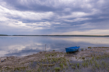 Naklejka na meble Evening landscape on the lake in early spring. The dramatic sky is reflected in the water.