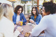© javiindy - Multi-ethnic group of students having a drink on the terrace of a street bar.