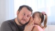 © Евгения Медведева - little cute daughter, 3 years old, tells her dad a secret, play together at home. Father's day. Handsome young man at home with his little cute girl are having fun together. Fatherhood concept, happy