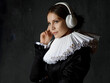 A noble lady in an old round collar enjoys music using modern headphones.