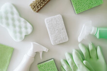 Green Protective Gloves, Sponges, Rag, Brush, Spray Cleaner Bottle With Chemical Detergent On White Background. Housework And Professional Eco Cleaning Service Supplies.
