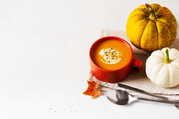 Wall Mural - Autumn pumpkin soup in red or orange bowl with vegetables