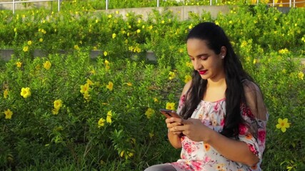 Wall Mural - An HD video of a Hispanic girl smiling while chatting on her smartphone in a park in Panama