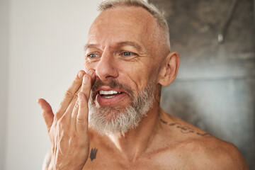 Mature man applying anti-aging cream on his face