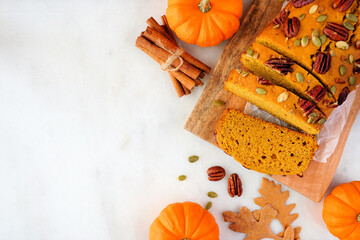 Poster - Autumn pumpkin bread sliced. Above view table scene over a white marble background. Copy space.