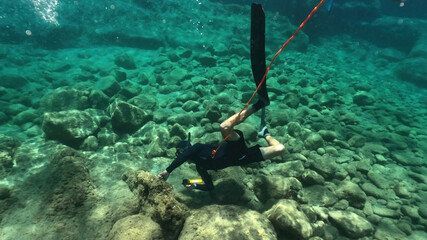 Underwater photo of spear fishing diver in deep emerald exotic paradise bay