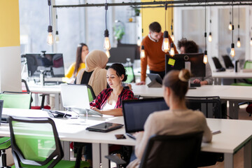 Creative team of young individuals working on desktop computers in a modern office space.