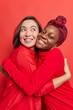 © wayhome.studio  - Vertical shot of diverse friendly women embrace with love have good relationships wear red clothes smile pleasantly pose indoor. Asian and Afro American females glad to meet after seperation