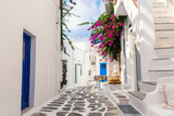Fototapeta Uliczki - Famous old town narrow street with white houses and Bougainvillea flower. Mykonos island, Greece