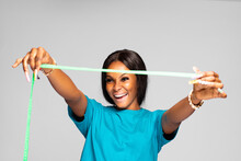 Beautiful Young Black Lady Excitedly Stretching A Measuring Tape In Front Of Her From Side To Side