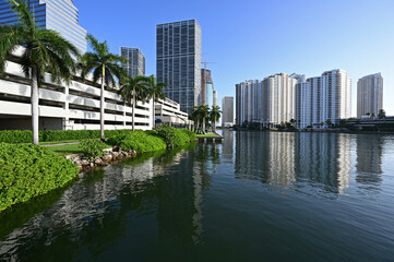 City of Miami, Florida skyline reflected in still water of Biscayne Bay at sunrise.