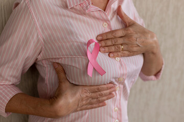 Wall Mural - woman with pink ribbon holding hand on chest. breast self-exam. pink October.