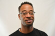 © SarahJ - African American male wearing glasses looks into the camera with a smile.