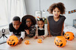 © Seventyfour - Group of African-American kids dressed in Halloween costumes posing with pumpkin pails indoors and looking at camera