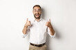 © Mix and Match Studio - Excited man in glasses showing thumbs up and looking amazed, agree and approve something great, recommending product, standing over white background