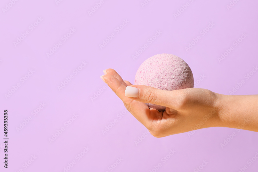 Female hand with lavender bath bomb on color background