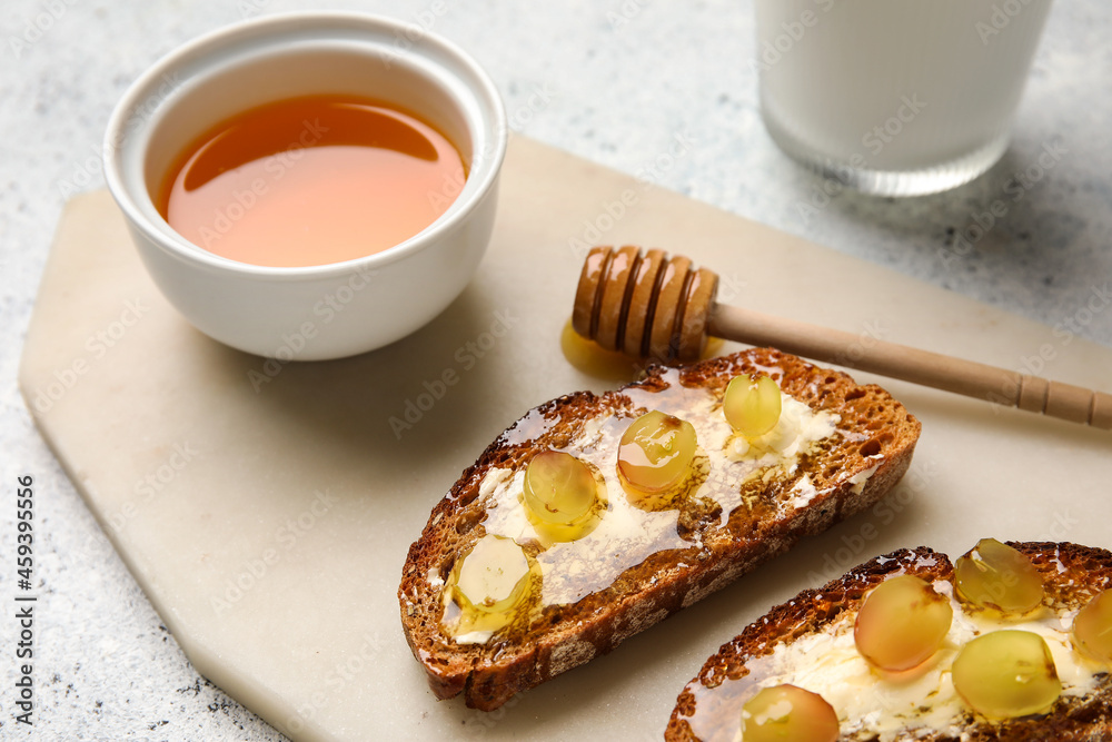 Delicious toasted bread with honey, butter and grape on white background, closeup