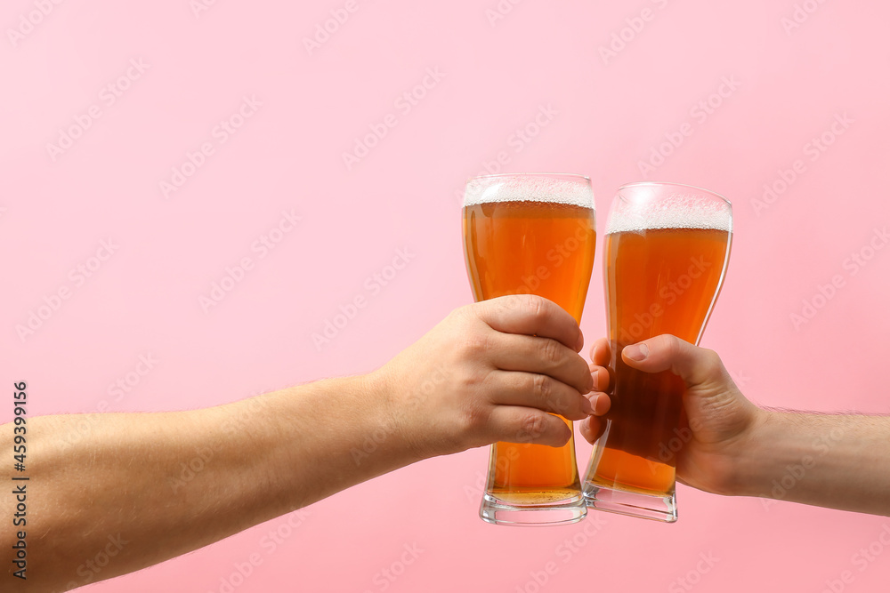 Hands with glasses of beer on color background