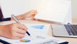 © photofriday - Close-up of businessman's hand checking market statistic data sheet on table