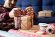 © Westend61 - Man tying ribbon bow on Christmas present at home