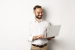 © Mix and Match Studio - Business. Handsome businessman working on laptop, answering messages and smiling, standing over white background