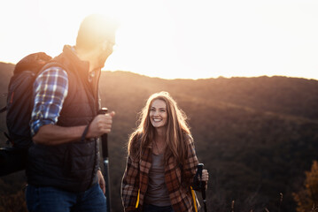 Couple hiking together in nature with backpacks at sunset.