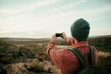 Wall Mural - Caucasian male photographer hiking in wilderness taking images on cellular device 