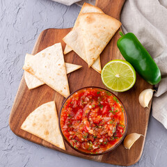 Tex-Mex cuisine, salsa Asada sauce with tortilla chips and lime, top view, square