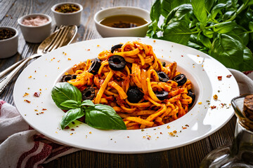 Sticker - Fettuccine and chicken nuggets with tomato and basil sauce with black  olives on wooden table