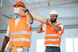 © fotofabrika - Two young men builders carrying wood planks on construction site, close up