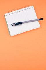 Sticker - Vertical shot of a notebook and a pen on an orange background - education concept