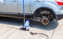 Car At The Tire Mounting With Removed Wheel On Pneumatic Jack