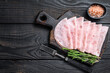 Sliced prosciutto ham on wooden cutting board. Black wooden background. Top view. Copy space