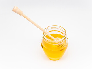 Wall Mural - Honey in a transparent glass jar with a wooden spoon isolated on a white background