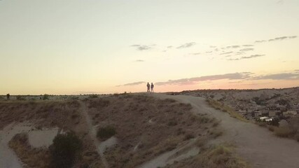 Canvas Print - A drone rotating shot of a couple on top of a rocky hill under the sky at sunset in Capadoccia, Turkey